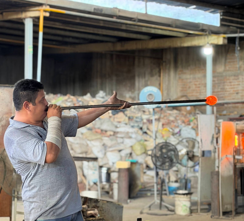 Glassblower shaping molten glass in a workshop.