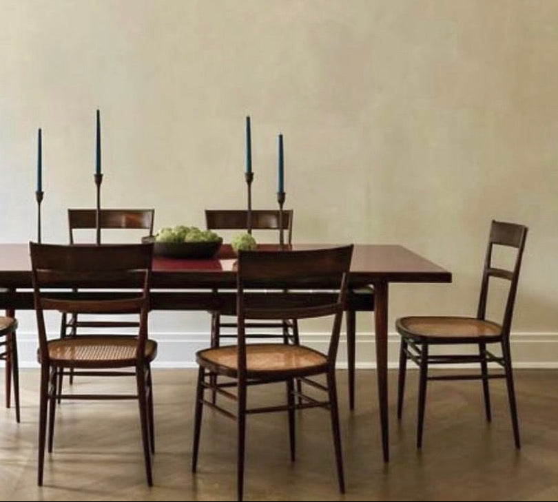 Dining room with wooden table and chairs, modern chandelier, and decorative sculpture.