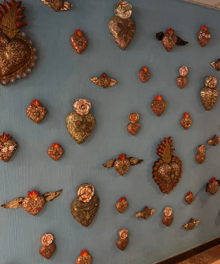 Decorative wall with various metal heart-shaped ornaments on a light blue background