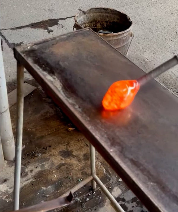 Glassblowing process with molten glass on a metal table