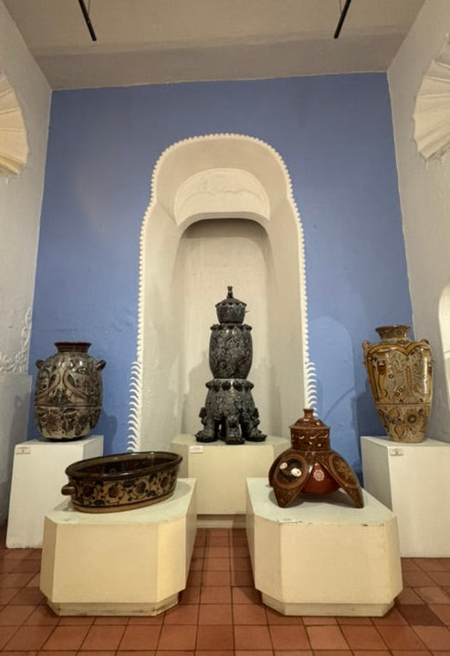 Decorative interior with vases on pedestals against a blue wall.